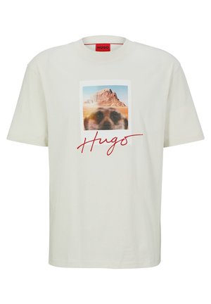 Wit T-shirt met foto van woestijnrotsformatie en vervaagd dierengezicht, rode "Hugo" handtekening onder de afbeelding aan de voorkant.
