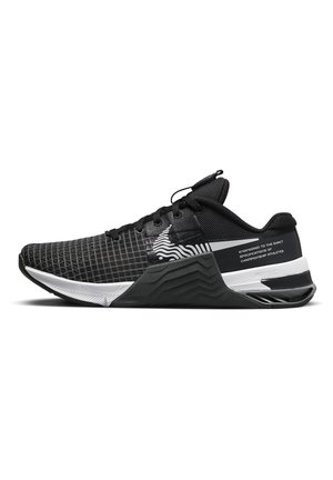 Black and white athletic sneaker with textured mesh upper, laces, zigzag midsole, and text reading "engineered to the exact specifications of championship athletes."