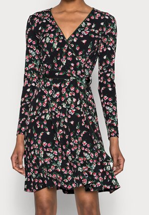 Zwarte wikkeljurk met lange mouwen en een bloemmotief van kleine rode, witte en groene bloemen, gestrikt in de taille.