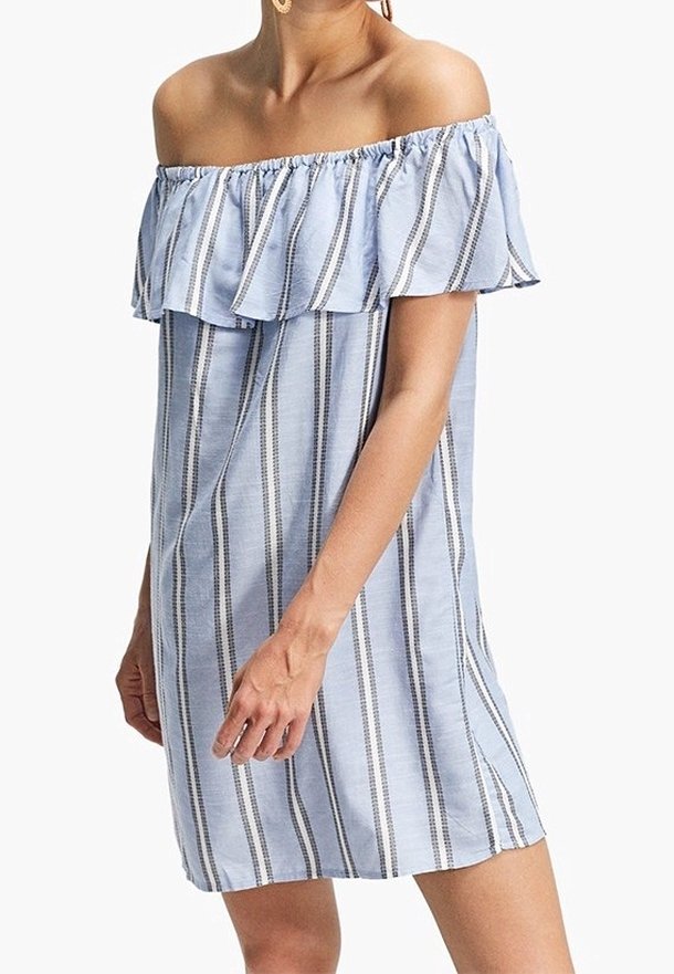 Femme portant une robe bleu clair épaule dénudée avec des rayures verticales blanches et foncées, dotée d'un col à volants et d'un ourlet court.