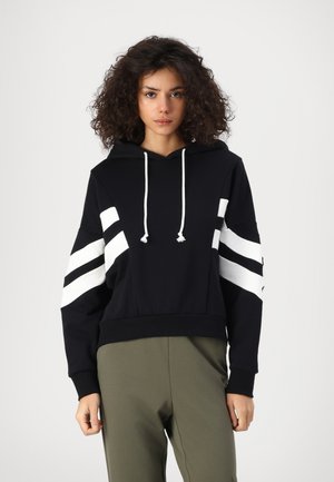 Black hoodie with white stripe accents on sleeves, drawstring hood, and ribbed cuffs. Paired with olive green pants.