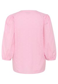 Puffi-hihainen vaaleanpunainen paita, jossa on pienten sydänten tekstuurikuvio. Kevyt kangas, pyöreä pääntie ja suora helma.