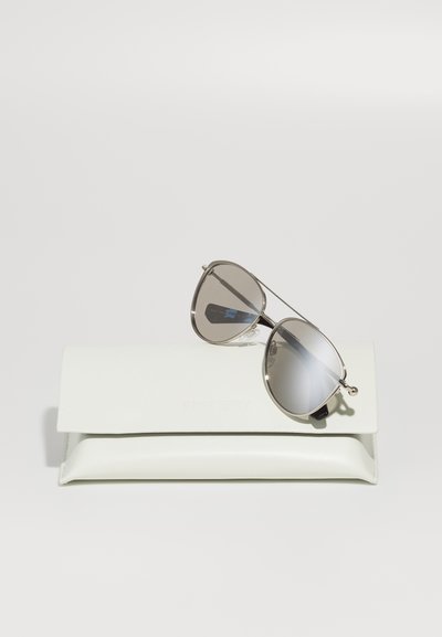Silver aviator solglasögon med grå spegelglas som vilar på en vit skyddande fodral präglat med varumärket.