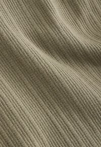 Tejido de punto texturizado de un color verde oliva apagado, con sutiles canaladuras y una apariencia suave y tejida.