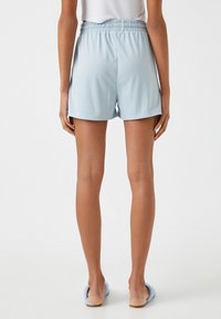 Pantalones cortos de color azul claro con una cinturilla elástica flexible, que presentan una textura suave y un corte relajado, terminando por encima del medio muslo.