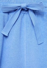 Ljusblå joggingbyxor i mjukt frottématerial. Har ett texturerat midjeband och en matchande rosett fram för justering.