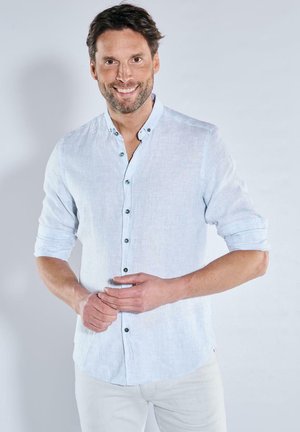 Helles blaues Leinenhemd mit langen Ärmeln, knöpfbarem Kragen und dunklen Knöpfen. Der Stoff hat eine subtile Textur und ein entspannter Schnitt.