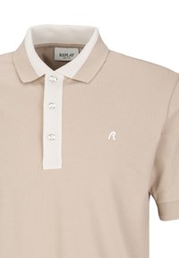 Beige polo shirt van textiel met een witte kraag, drieknoopsluiting en een klein wit logo op de borst.