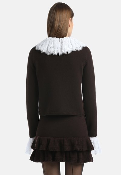 Pull en maille marron avec un col en dentelle blanche à volants, présentant une silhouette ajustée et une jupe à volants, sur fond uni.