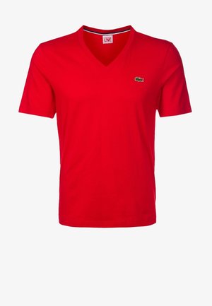 T-shirt rossa a maniche corte con scollo a V e un piccolo logo verde di coccodrillo sul petto sinistro, mostrata su sfondo bianco.