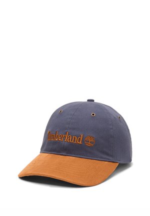 Marineblauwe en bruine Timberland honkbalpet met geborduurd logo en ventilatieoogjes op een witte achtergrond.