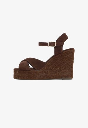 Sandale compensée en suédé marron avec semelle plateforme tressée, brides croisées à l'avant et bride de cheville réglable avec boucle en métal.