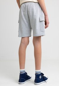 Šedé bavlněné cargo kraťasy s bočními kapsami, elastickým pasem a volným střihem. Slaďuje se s námořnickými vysokými sneakersey a pruhovanými ponožkami.