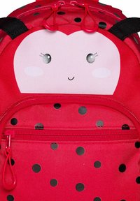 Roter Rucksack mit einem Marienkäfer-Design, einer lachenden Gesicht auf einem rosa Panel, gepunktetem Muster und einer Reißverschlusstasche mit pinkfarbener Hardware.