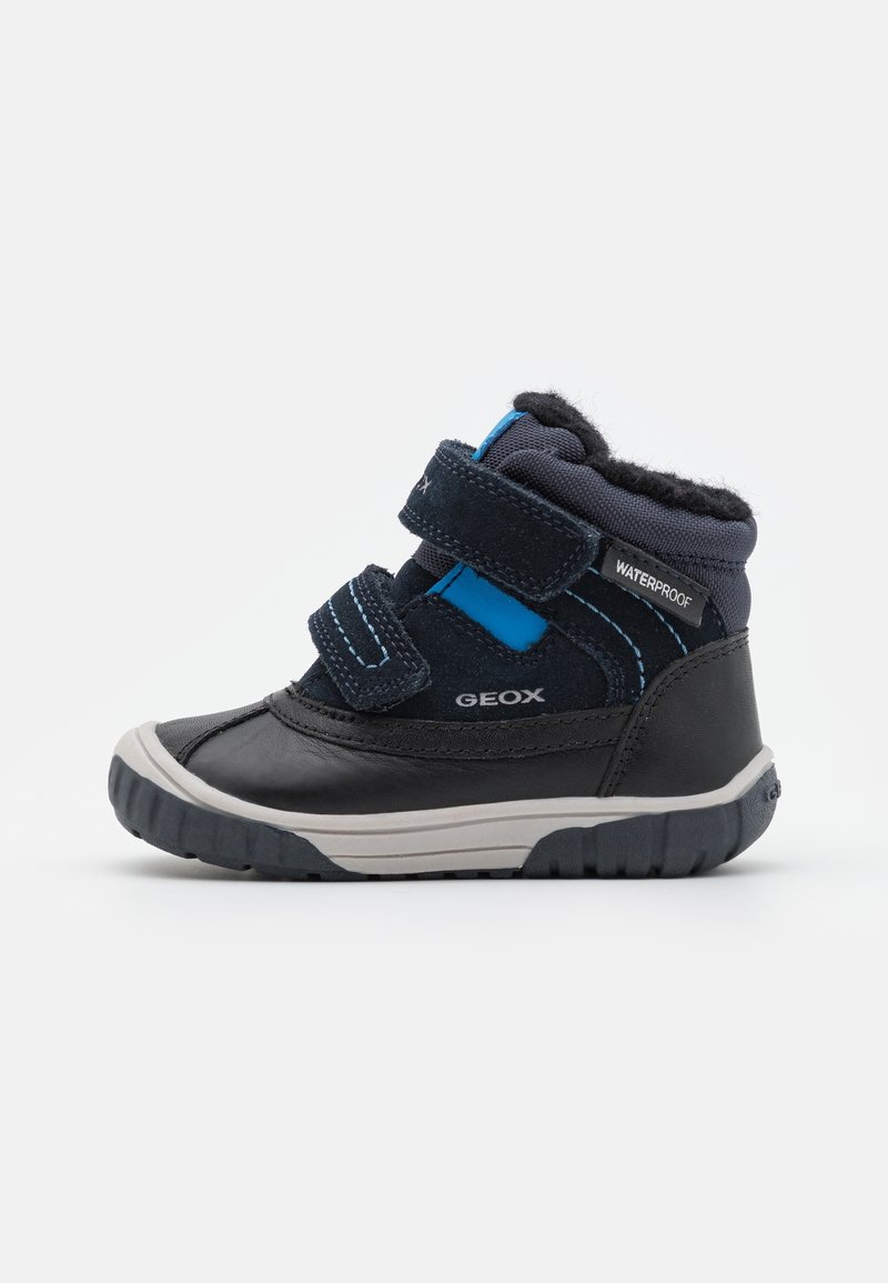 Bottine imperméable noire et bleu marine, avec deux bandes Velcro, tige texturée, semelle en caoutchouc et accents bleus contrastants.