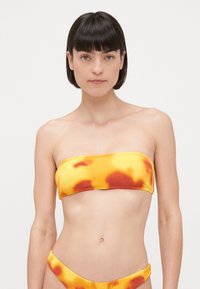 Gul bandeau bikini topp med oransje og rød tie-dye mønster. Ribbete tekstur, sømløst design, kombinert med en matchende bikini bunn.
