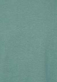 T-shirt turquoise en tissu doux et texturé avec une légère élasticité ; présente un design uni sans motifs ni accents.