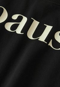 Tela negra con la palabra "pausa" en texto negrita de color claro. La textura parece suave, con un ligero brillo en algunas áreas.