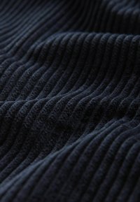 Laine sininen ribbausmateriaali pehmeällä pinnalla, jossa on voimakkaat pystysuorat viivat. Pintaa näyttää olevan ylellinen ja samettinen, jossa on hienostunut kiilto.