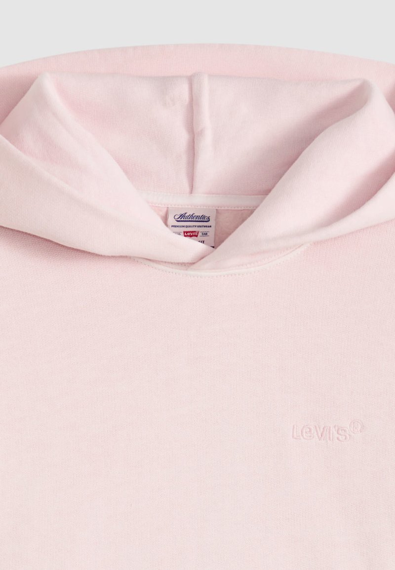 Sweat à capuche rose clair avec une texture douce. Présente un petit logo Levi's embossé sur la poitrine et une capuche avec cordon de serrage.