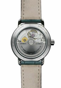 Automatic watch with stainless steel case, transparent back, yellow and silver gears, beige leather strap, and engraved details on the casing.