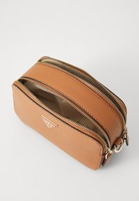 Braune strukturierte Kunstledertasche mit zwei Reißverschlussfächern, goldenen Hardware-Details und einem dreieckigen Logo auf der Vorderseite.