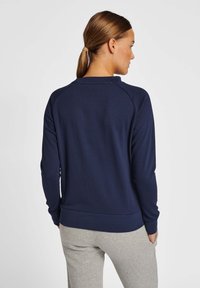 Sweat-shirt bleu marine avec un col rond, des manches raglan longues et une taille ajustée, fabriqué à partir d'un tissu doux et confortable.