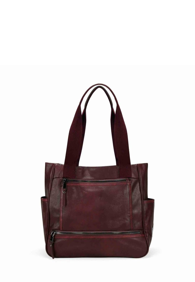 Sac cabas en cuir rouge foncé avec deux longues anses, poche zippée à l'avant, compartiment zippé inférieur et poches latérales ouvertes.