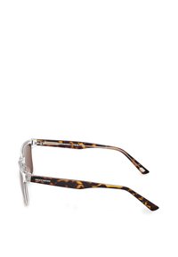 Aurinkolasit, joissa on kirkkaat kehykset ja ruskeat sävyttävät linssit. Kaukana on kilpikonnakuosiset templet mustilla ja kultaisilla yksityiskohdilla.