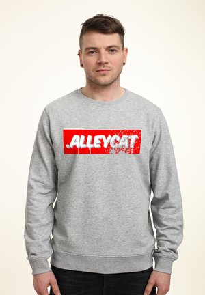 Šedá mikina s dlouhými rukávy, na které se nachází výrazný červený obdélníkový grafický text "ALLEYCAT" v bílé barvě, s opotřebovaným designem.