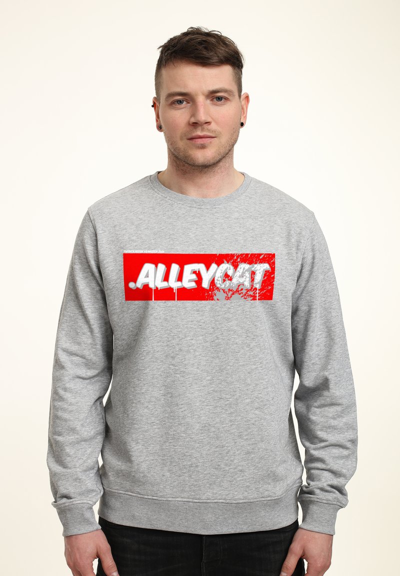 Grå sweatshirt med långa ärmar som har en djärv röd rektangulär grafisk text "ALLEYCAT" i vitt, med en sliten design.