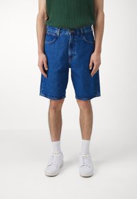 Jeans šorts u svijetloplavoj boji s opuštenim krojem, s pet džepova, narančastim šavovima i pojasom s metalnim gumbom.