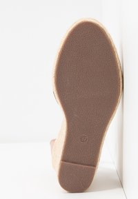 Sandale compensée espadrille avec une semelle en caoutchouc brun texturée, matériau beige ressemblant à de la paille en dessous, taille 37 indiquée sur la semelle.
