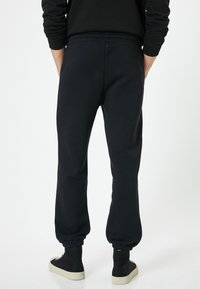 Sorte sweatpants med afslappet pasform, elastisk talje og ribbede manchetter, fremstillet af blødt stof med en glat overflade.