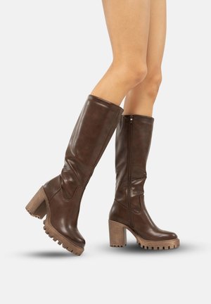 Botas de cuero marrón hasta la rodilla con un tacón grueso, cremallera lateral y suela texturizada. Acabado liso con detalles de costura sutiles.