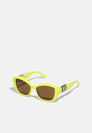 Occhiali da sole a forma di occhio di gatto giallo neon con lenti brunite, dotati di un accento in metallo argentato sulle tempie. Montatura in plastica liscia.