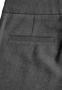 Tessuto grigio scuro con una texture liscia; presenta una tasca a filetto sul retro, che indica un design su misura.