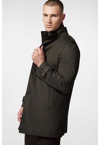 Ciemnozielony trencz z wysokim kołnierzem, zapinany na guziki z przodu oraz z kieszeniami po bokach. Charakteryzuje się gładką teksturą i zorganizowanym designem.