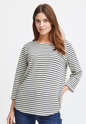 Langærmet bluse i en cremet stof med marineblå prikmønstre. Designet har en rund halsudskæring og en afslappet pasform.