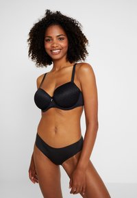 Zwarte bh met gestructureerde cups en een textuurpatroon, voorzien van verstelbare bandjes en een kleine centrale versiering. Combineert met zwarte slips.