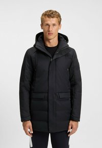 Black padded jacket featuring a hood, zip closure, and two front pockets. Smooth texture with a sleek, modern design.
