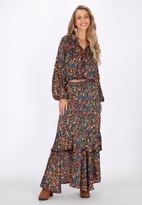 Set colorato composto da una blusa a maniche puff con fantasia e una gonna maxi a strati, entrambi nei toni del blu, arancione e verde.