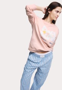 Felpa rosa chiaro con grafica bianca "Peace & Love" e accento giallo. Pantaloni da pigiama a righe blu e bianche. Vestibilità comoda, tessuto morbido.