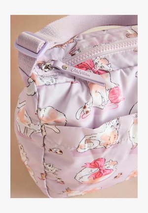 Sac lilas présentant des illustrations de chats ludiques, incluant des pelotes de fil et des nœuds, avec un détail de fermeture éclair et de bandoulière visible. Fond doux.