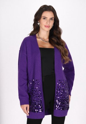 Lila Strickjacke aus Strickstoff mit funkelnden Taschen. Offenes Vorderdesign mit langen Ärmeln und gerippten Bündchen.