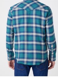 Geruite shirt in blauwgroen, wit en marineblauw met lange mouwen, knoopsluiting bij de mouwen en een puntkraag. Heeft een visgraatstructuur.