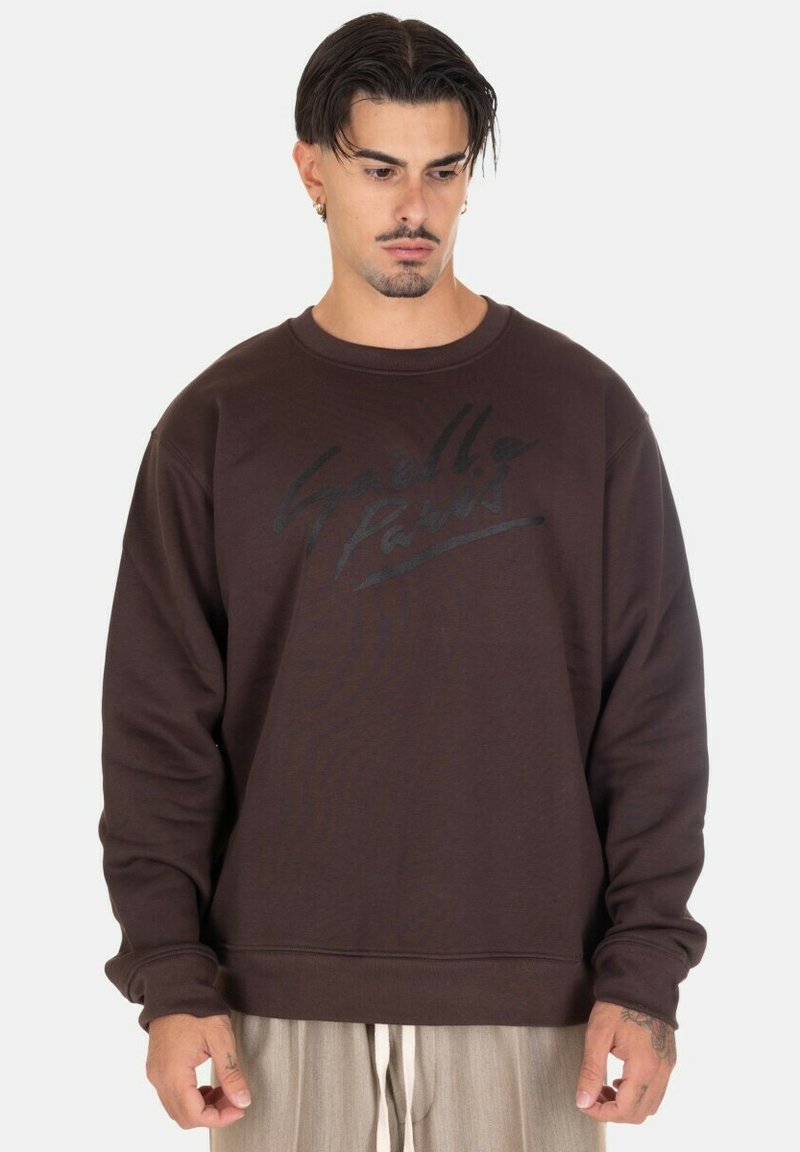 Felpa marrone realizzata in tessuto morbido, con colletto rotondo e maniche lunghe. Design con scritte nere sul davanti; vestibilità comoda.