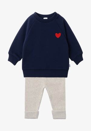 Marineblaue Sweatshirt mit rotem Herzakzent, kombiniert mit hellgrauen Strickhosen mit Bündchen. Weiches, lässiges Zweiteiler-Outfit.