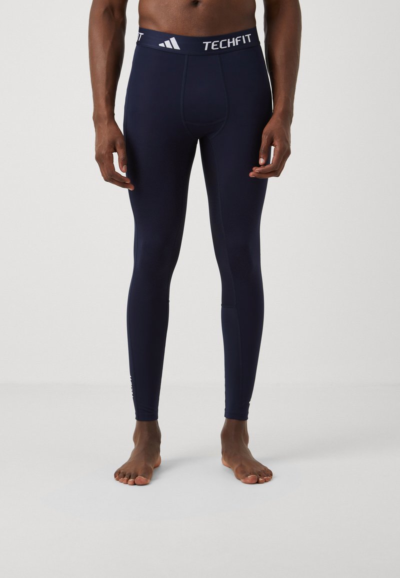 Marine Navy Techfit compressie legging met een nauwsluitende pasvorm, gladde textuur en witte gebrandmerkte tailleband. Eenvoudig ontwerp zonder extra patronen.