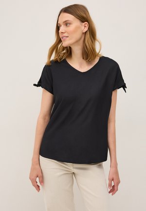 Haut noir à manches courtes avec un col en V et un léger drapé aux manches, fabriqué en tissu lisse avec une coupe décontractée.